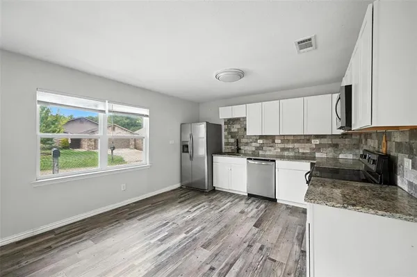 a kitchen with granite countertop wooden floors and white stainless steel appliances