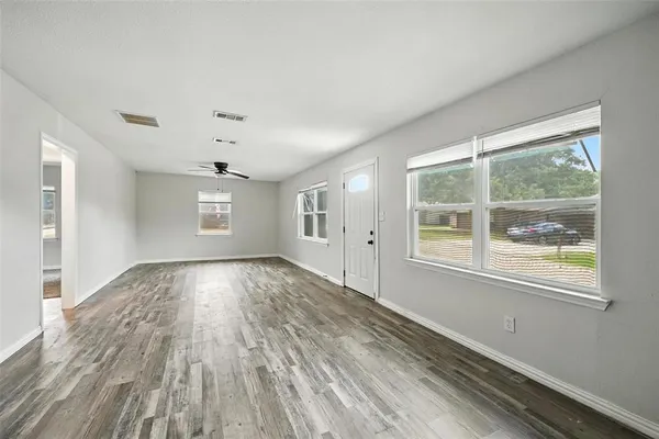 a view of an empty room with wooden floor and a window