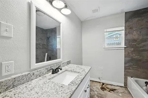 a bathroom with a granite countertop sink and a mirror