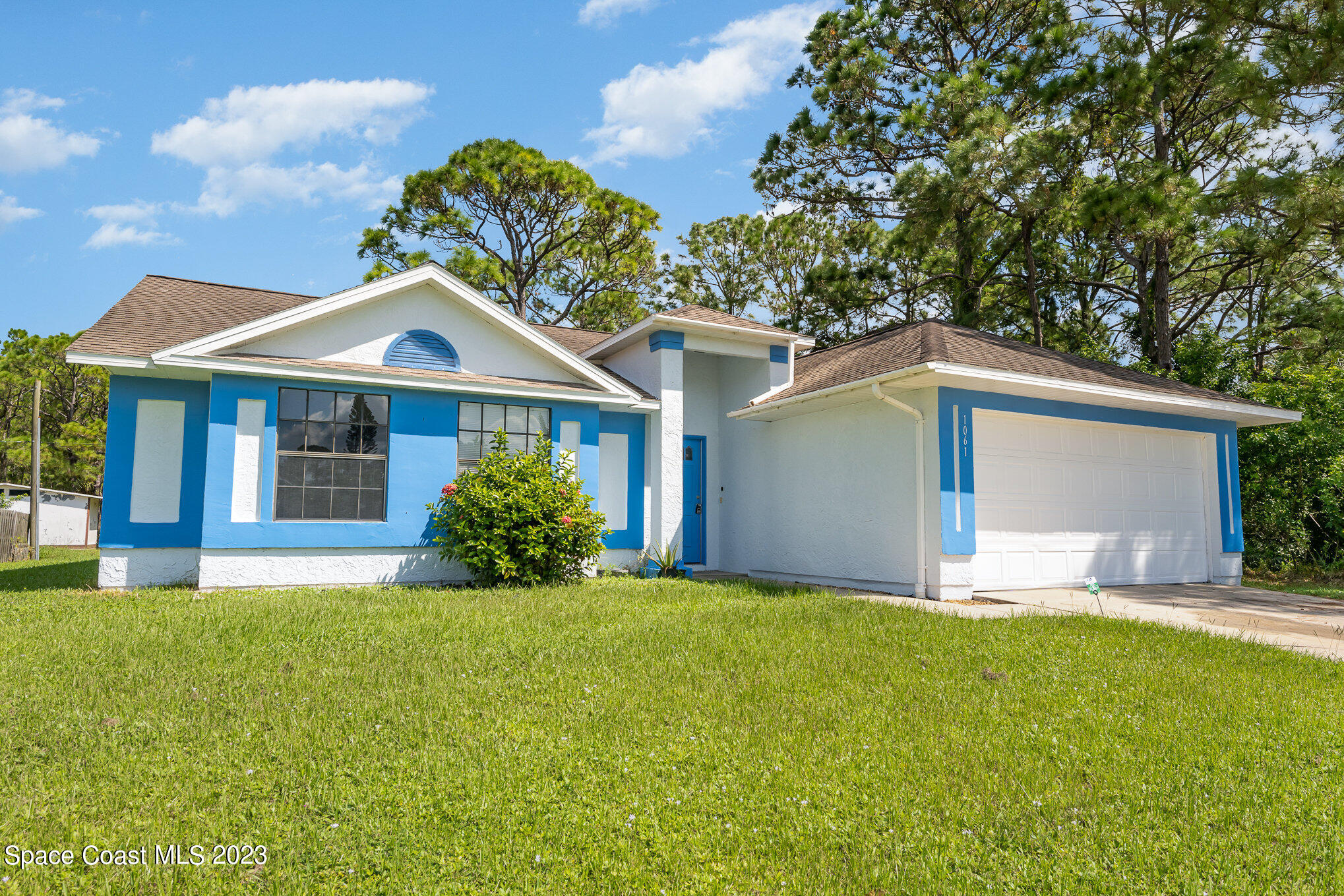 1061 Spring Street Northwest Palm Bay, FL 32907 - Photo 1 of 23 a front view of a house with a garden and yard