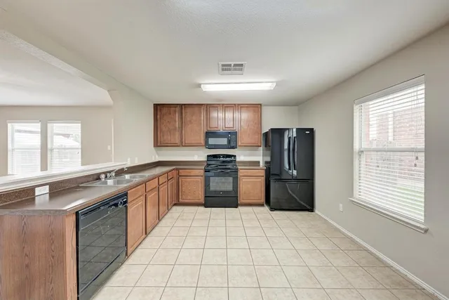 a large kitchen with a stove top oven a sink a counter space and cabinets