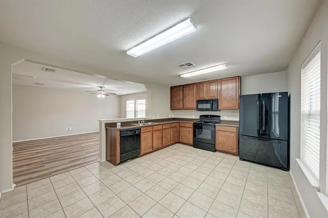 a kitchen with granite countertop a refrigerator and a stove top oven