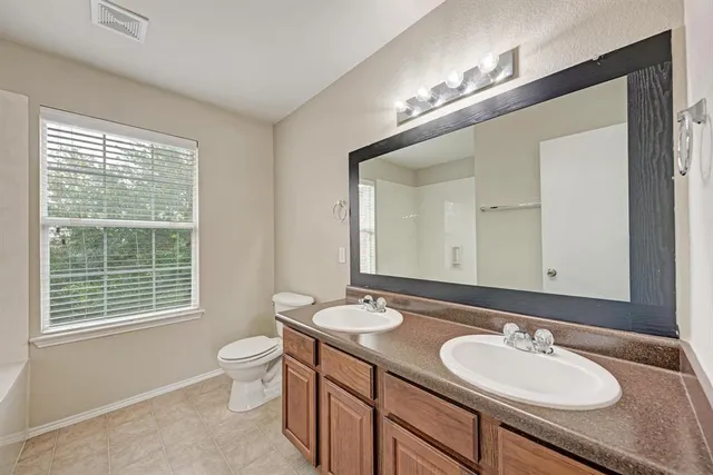 a bathroom with a double vanity sink a toilet and a mirror