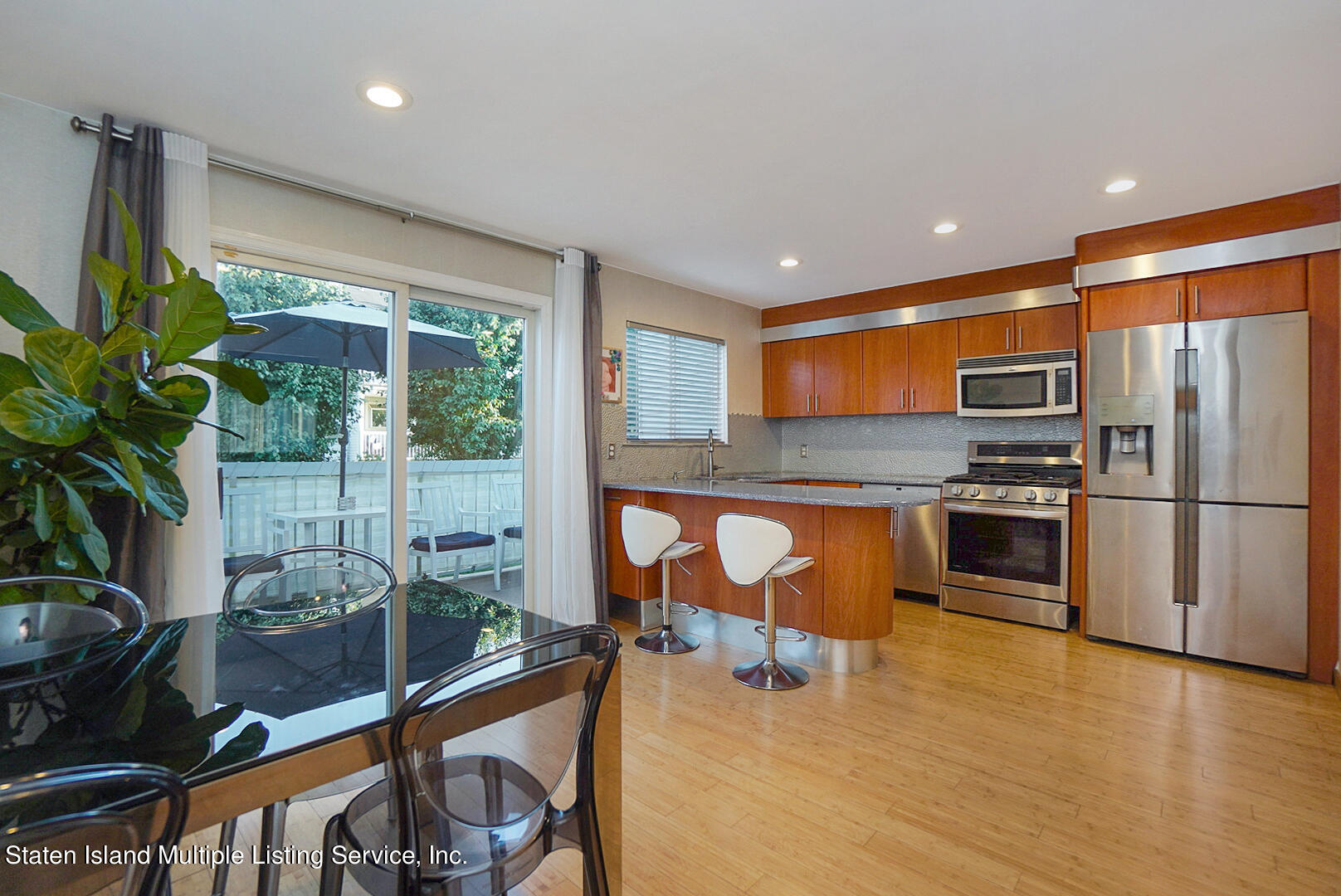 114 Commodore Drive Staten Island, NY 10309 - Photo 14 of 31 a kitchen with stainless steel appliances a stove a refrigerator a sink a dining table and chairs with wooden floor
