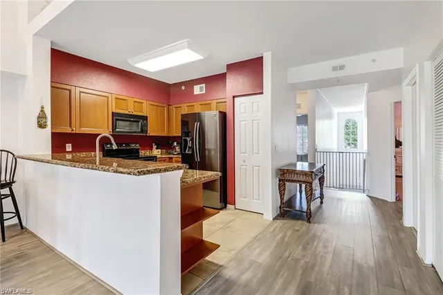 a kitchen with stainless steel appliances granite countertop a refrigerator a stove and a wooden floors