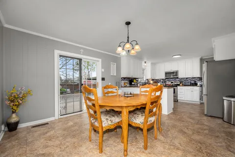 a view of a dining room and livingroom with furniture wooden floor a chandelier