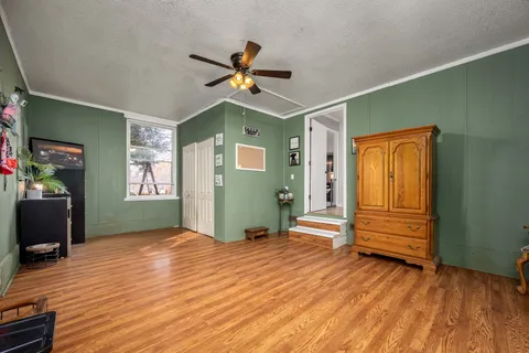 a view of empty room with wooden floor and fan