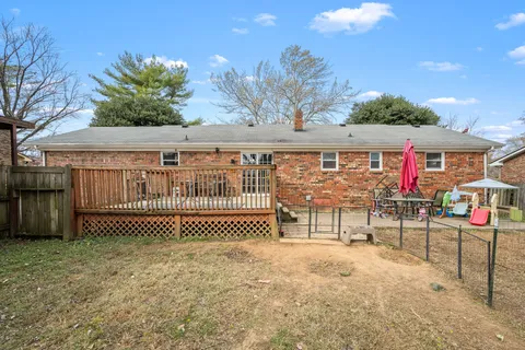 a view of wooden house with a yard and large trees