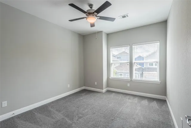 an empty room with a window and a ceiling fan