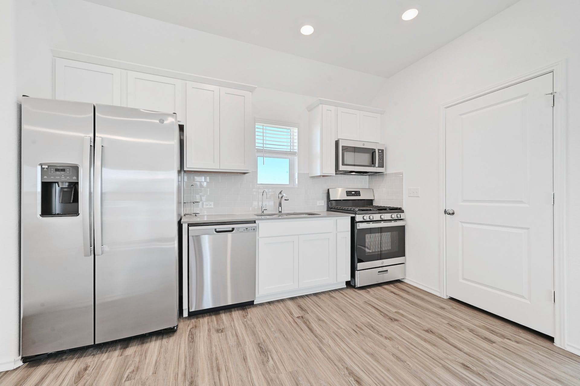 139 Rioja, Unit GARAGE APARTMENT Kyle, TX 78640 - Photo 10 of 16 A well-equipped kitchen features sleek stainless steel appliances, crisp white cabinetry, and wood-look flooring.