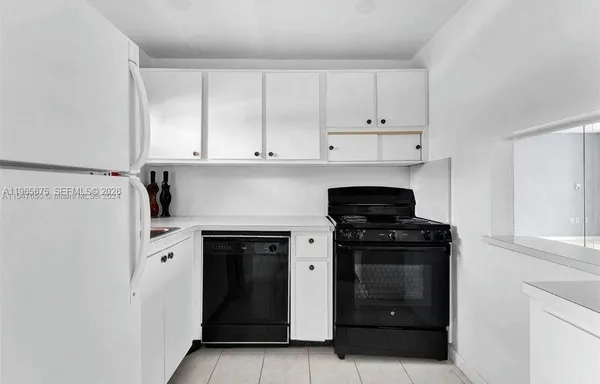 a kitchen with white cabinets and black appliances