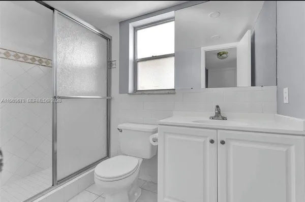 a bathroom with a toilet a sink a mirror a window and vanity