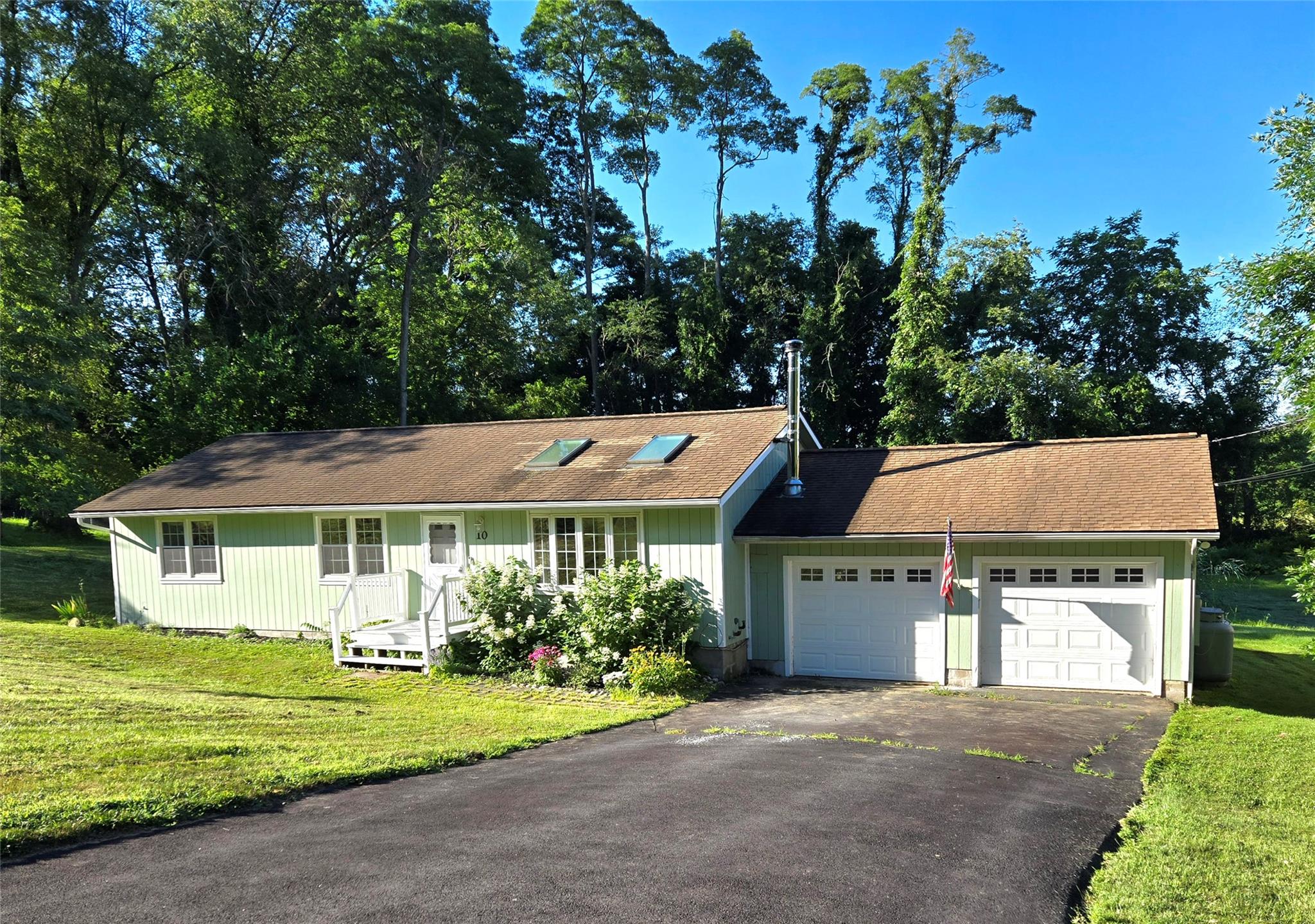 Ranch-style home featuring an attached garage, asphalt driveway, a front yard, and board and batten siding