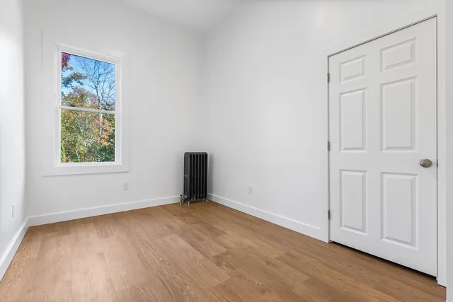an empty room with wooden floor and window