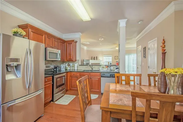 a kitchen with stainless steel appliances granite countertop a refrigerator a stove and a dining table with wooden floor