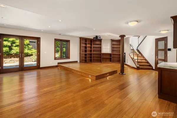 a view of an empty room with wooden floor and windows