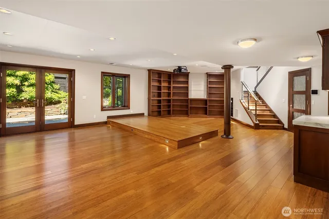 a view of an empty room with wooden floor and windows