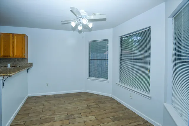 a view of an empty room with window and chandelier fan
