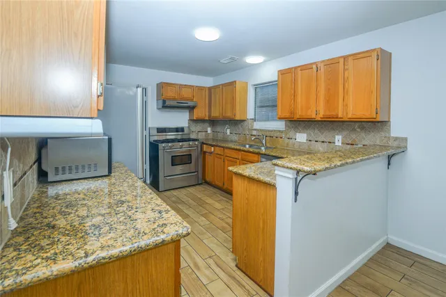a kitchen with stainless steel appliances granite countertop sink stove and refrigerator