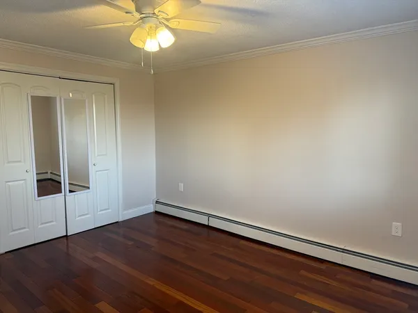 an empty room with wooden floor fan and windows