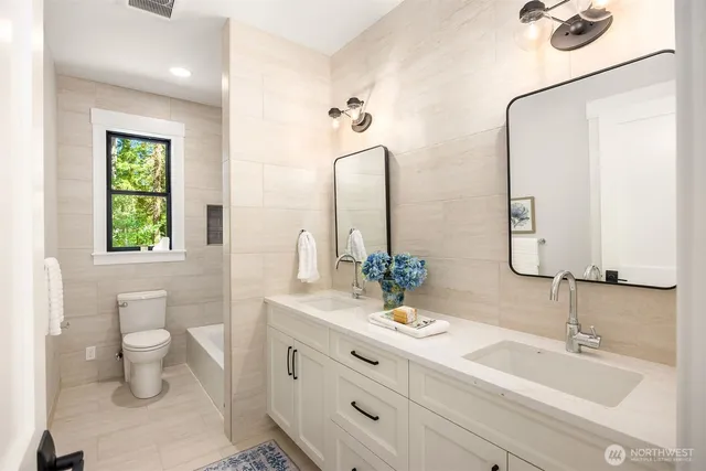 a bathroom with double vanity sinks a toilet and a mirror