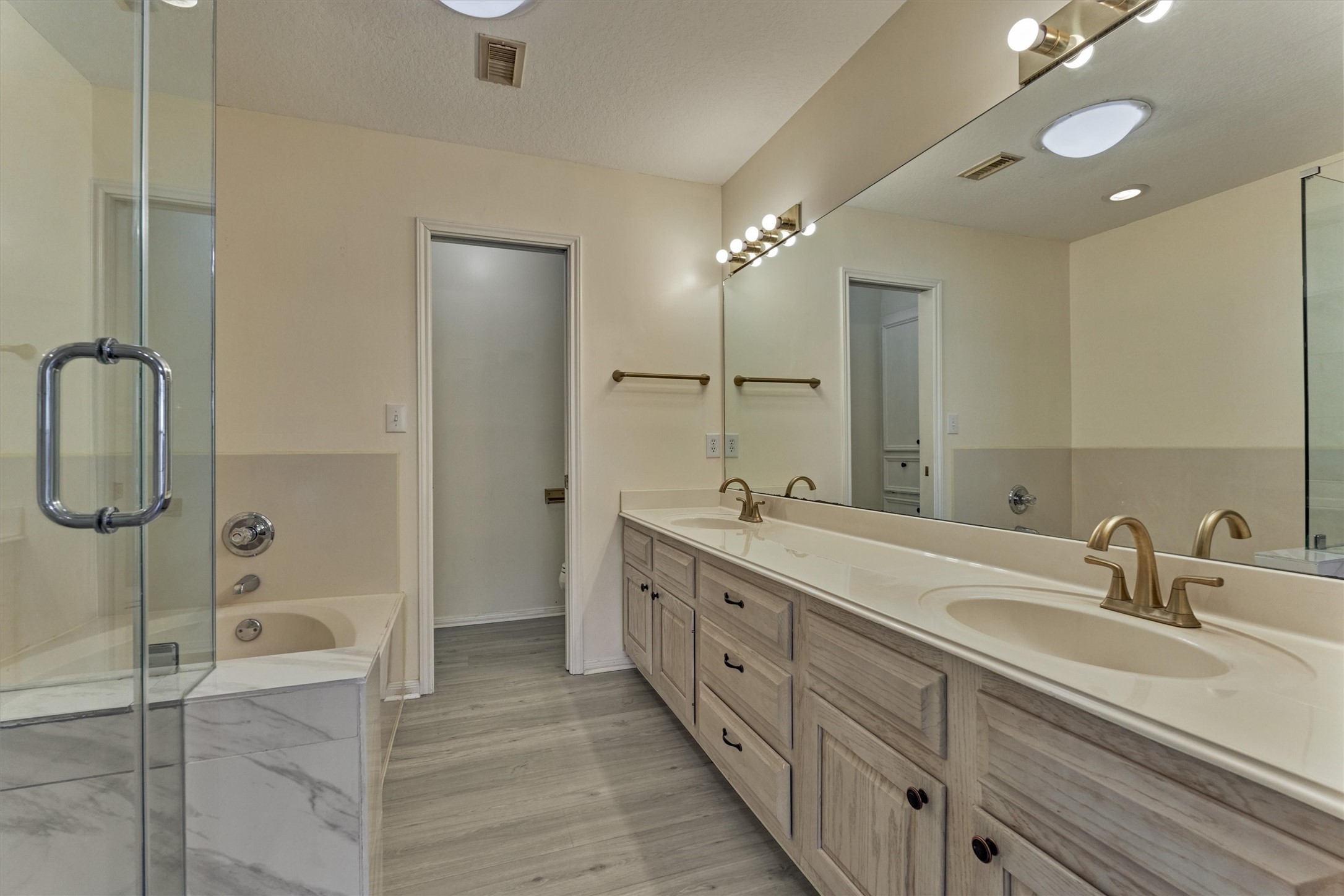 14420 Walters Road, Unit 26 Houston, TX 77014 - Photo 29 of 45 Spacious bathroom featuring a dual-sink vanity with ample storage, modern fixtures, a glass-enclosed shower, and a separate bathtub. Neutral tones and well-lit with a skylight and vanity lighting.