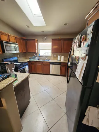 a kitchen with stainless steel appliances a stove a refrigerator a sink a microwave oven and a dining table with wooden floor