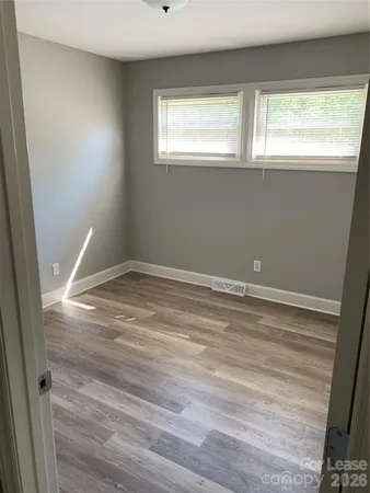 a view of empty room with window and wooden floor