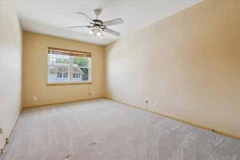 an empty room with a chandelier fan and windows