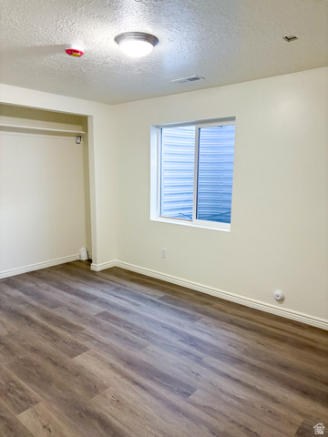 1666 West Foxberry Road Santaquin, UT 84655 - Photo 23 of 23 Unfurnished bedroom featuring a textured ceiling, dark wood finished floors, and a closet