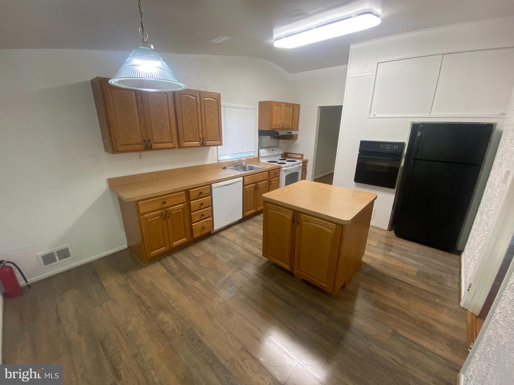 11602 Le Baron Terrace Silver Spring, MD 20902 - Photo 7 of 24 a large kitchen with a refrigerator a stove a sink dishwasher and a dining table with wooden floor