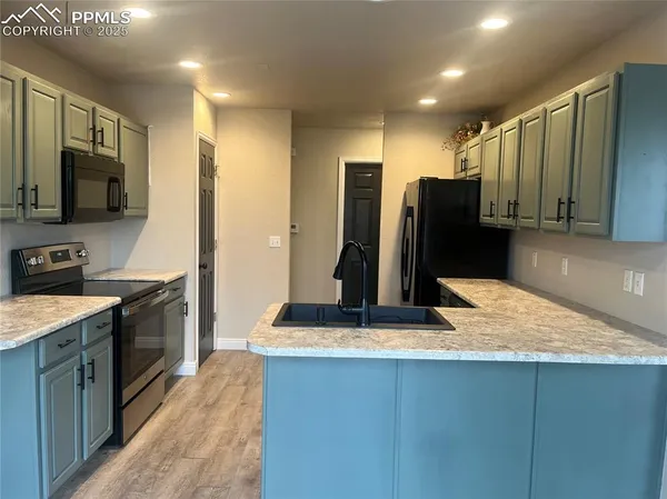 a kitchen with stainless steel appliances kitchen island granite countertop a refrigerator a stove and a sink