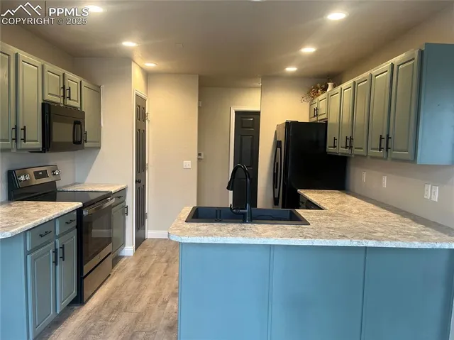 a kitchen with stainless steel appliances kitchen island granite countertop a refrigerator a stove and a sink