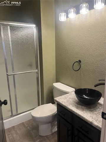 a bathroom with a granite countertop sink a toilet and shower