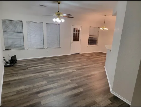 en empty room with wooden floor and ceiling fan