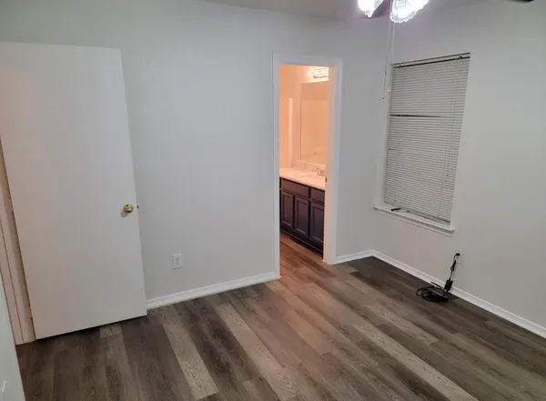 an empty room with wooden floor cabinet and windows