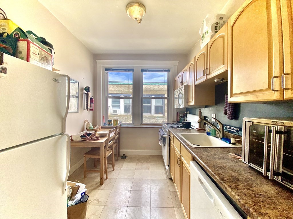 1691 Commonwealth Avenue, Unit 31 Boston, MA 02135 - Photo 3 of 12 a kitchen with stainless steel appliances granite countertop a sink a stove counter space and a window