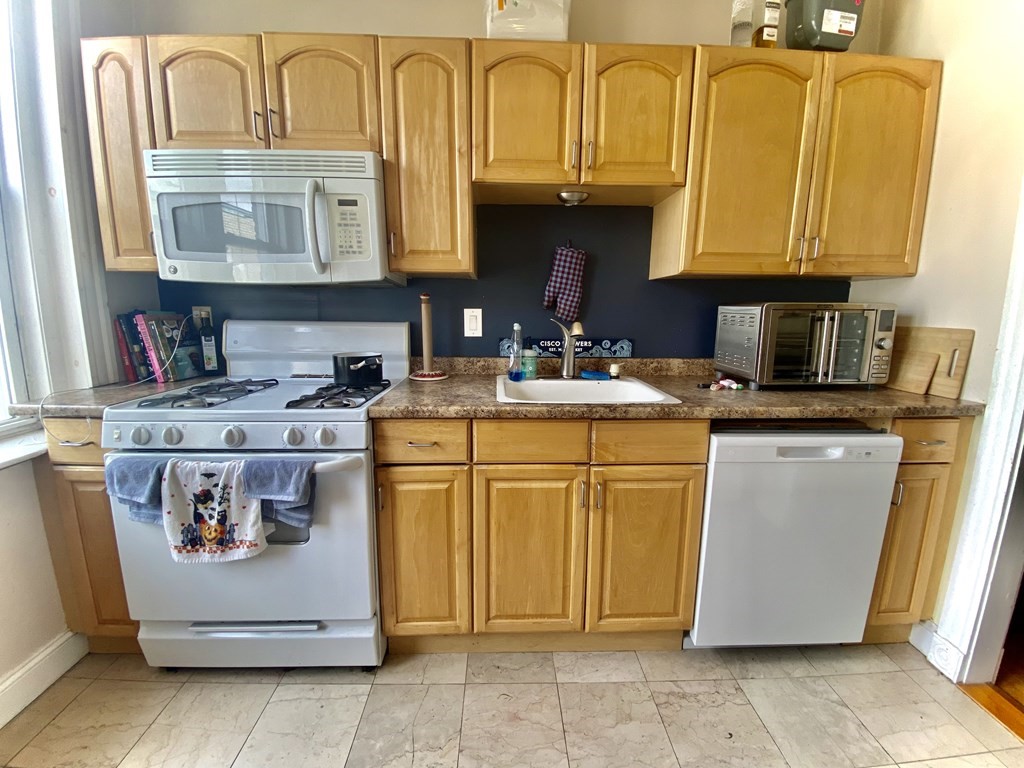 1691 Commonwealth Avenue, Unit 31 Boston, MA 02135 - Photo 4 of 12 a utility room with stainless steel appliances granite countertop a stove a sink and a microwave