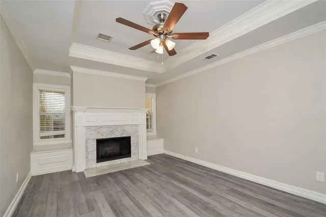 a view of a livingroom with a fireplace a ceiling fan and wooden floor