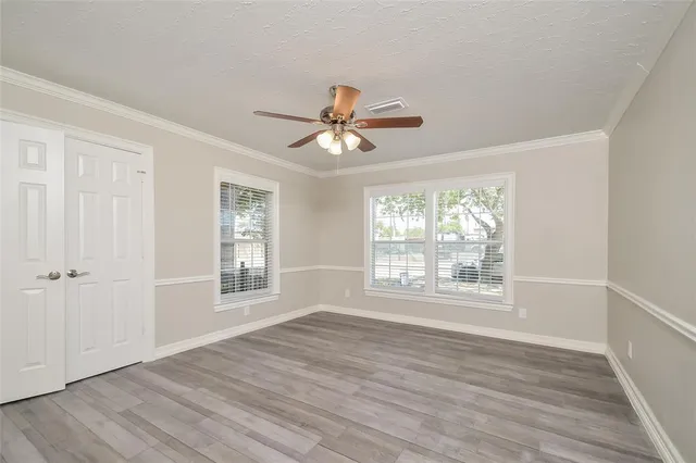 a view of an empty room with a window and a chandelier fan