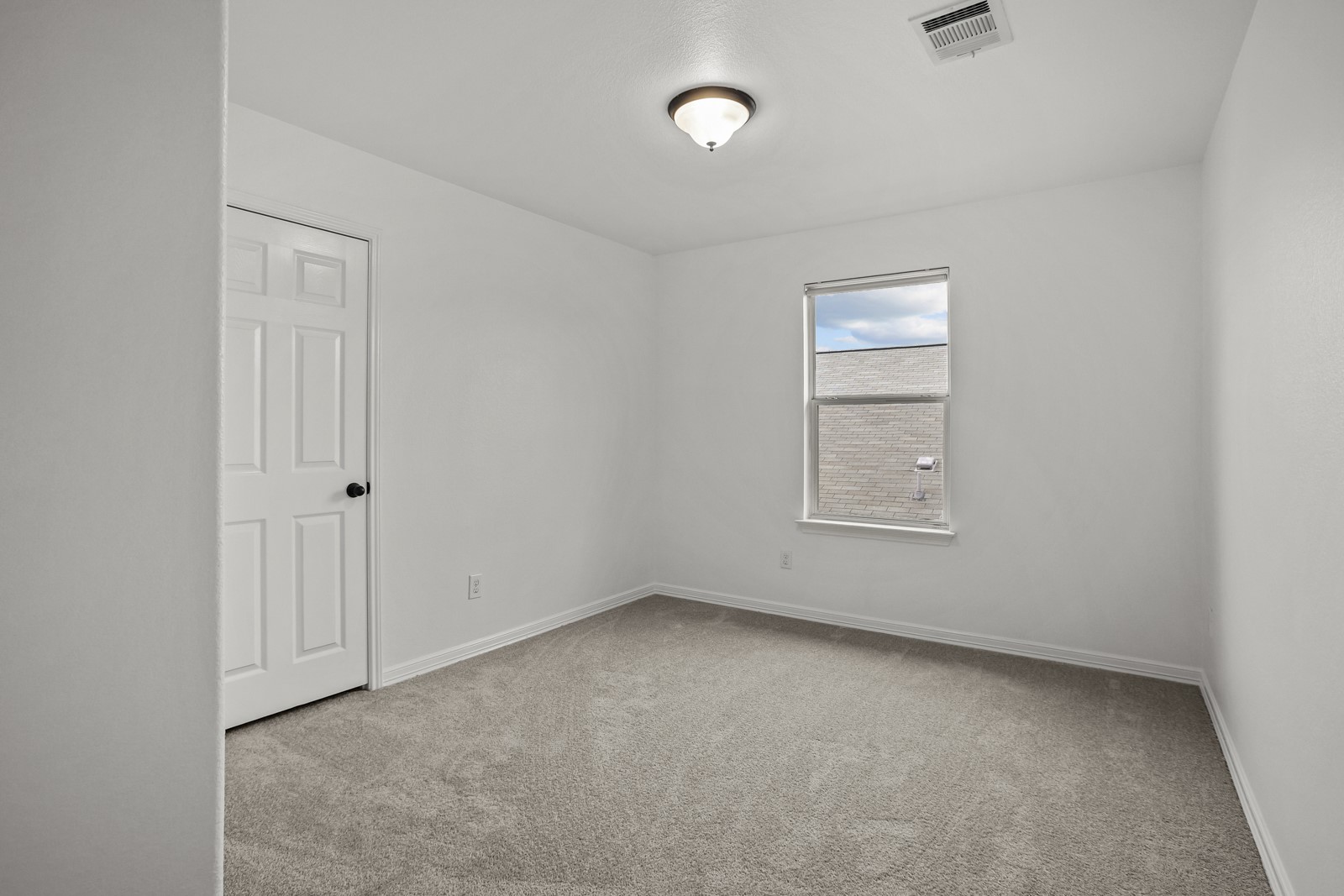245 Razzmatazz Trail Buda, TX 78610 - Photo 28 of 37 Neutral-toned carpeting and white walls in this room, featuring a white paneled door with black hardware, a single window, and an overhead flush-mount light fixture