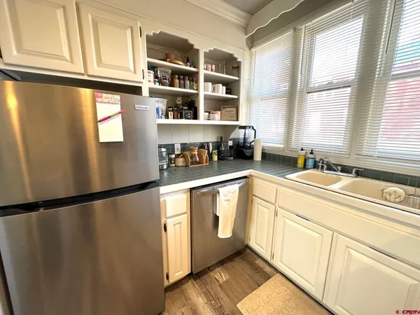 a kitchen with stainless steel appliances granite countertop a refrigerator a sink a stove and a window with wooden floor