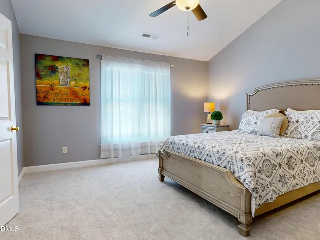 a bedroom with a bed a lamp and a flat tv screen