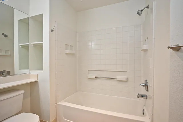 a white bath tub sitting next to a white toilet and a shower