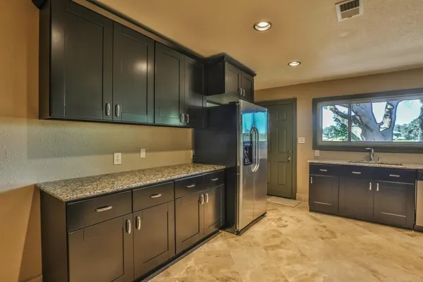 a kitchen with granite countertop a stove top oven and refrigerator