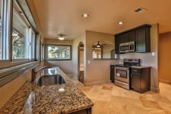 a kitchen with granite countertop a refrigerator and a stove top oven