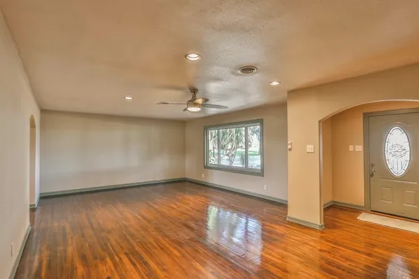 a view of an empty room with wooden floor and a window