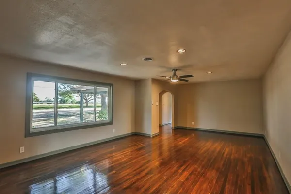 a view of an empty room with window and wooden floor