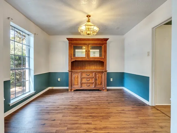 a view of an empty room with window and wooden floor