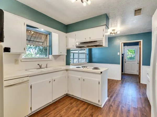 a kitchen with a sink cabinets wooden floor and stainless steel appliances